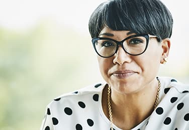 Woman with glasses and polka dot shirt looking at camera