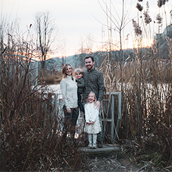 Ewa and Danny's family standing in front of a pond surrounded by tall grasses