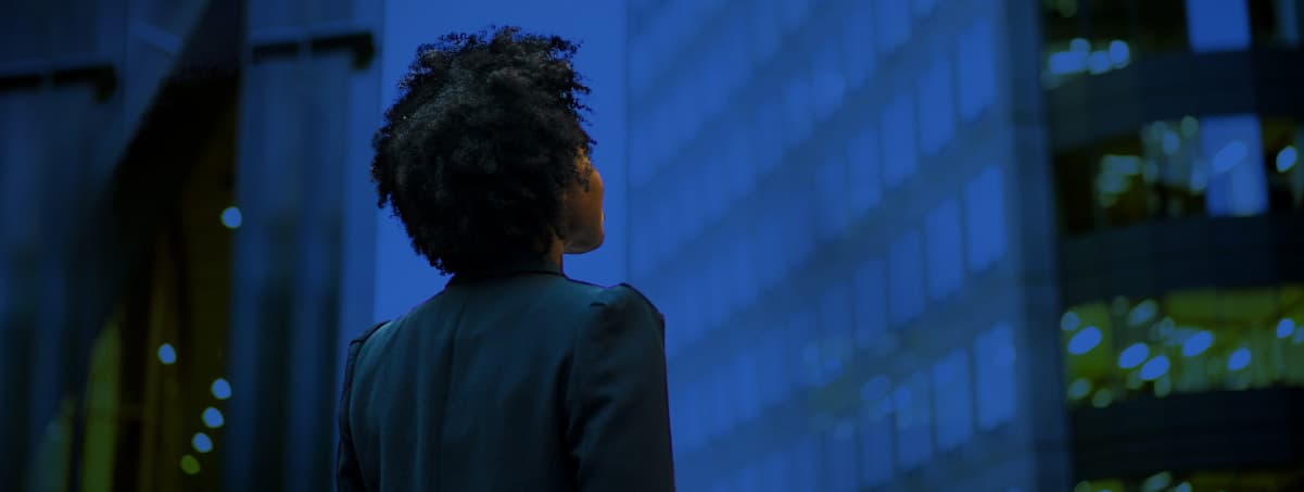 Person looking up at skyscrapers in dark blue scene