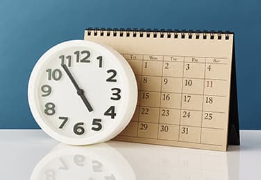 Calendar with analog clock in front of it